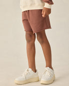 Child wearing brown jogger shorts against a white background.