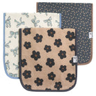 A set of three square burp cloths with different floral patterns. One has a blue background with white flowers, another is beige with black flowers, and the third is blue with a polka dot pattern.