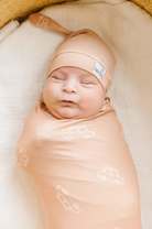 swaddle blanket for babies that is orange with white trucks and matching hat 