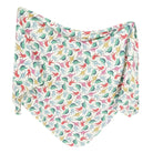 A knit swaddle blanket with a pattern of various dinosaurs from the Jurassic Park era in a multicolor design on a white background.
