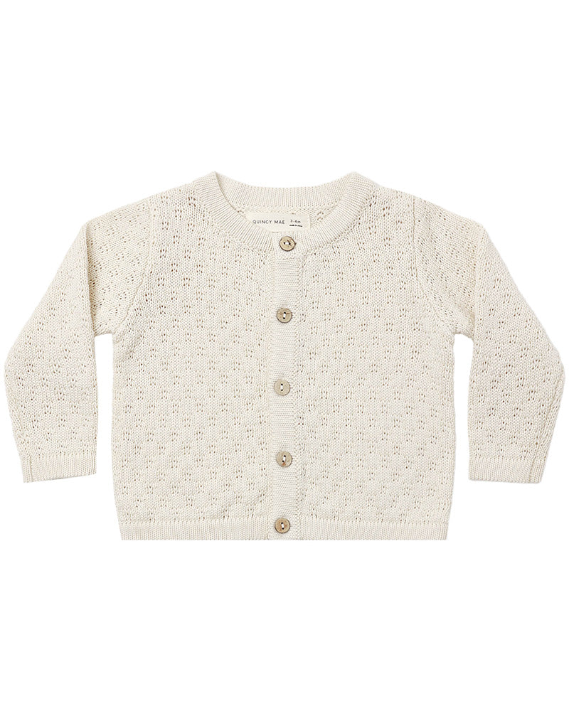 An off-white knit cardigan sweater for toddlers, featuring a textured open-knit pattern and four brown buttons down the front, displayed flat against a white background.