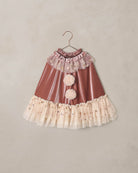 Children's costume cape with ruffles and star details on a beige background