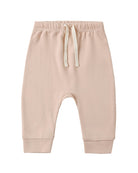 A pair of baby jogger pants in a soft, light peach-beige color, featuring an elastic waistband with a cream-colored drawstring and ribbed ankle cuffs, shown against a plain white background.