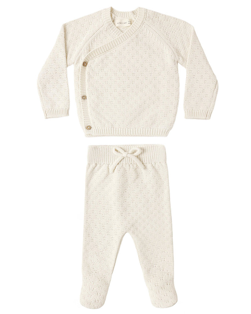 A baby knit two-piece outfit set in cream/off-white, featuring a long-sleeve wrap-style cardigan with brown buttons and matching footed pants with an elastic waist and bow.
