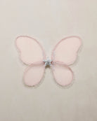 Pink butterfly-shaped wings with a central star on a beige background