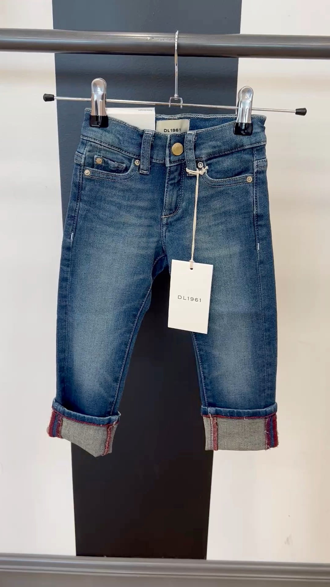 Blue jeans with a tag on a rack against a neutral background