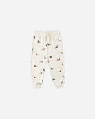 Cream-colored jogger pants with small dog pattern on a white background