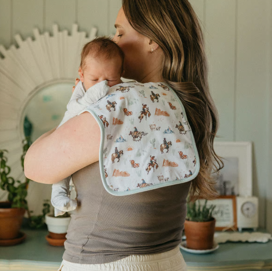 woman holding baby with a cowboy print burp cloth