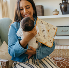 woman holding baby with horse print burp cloth