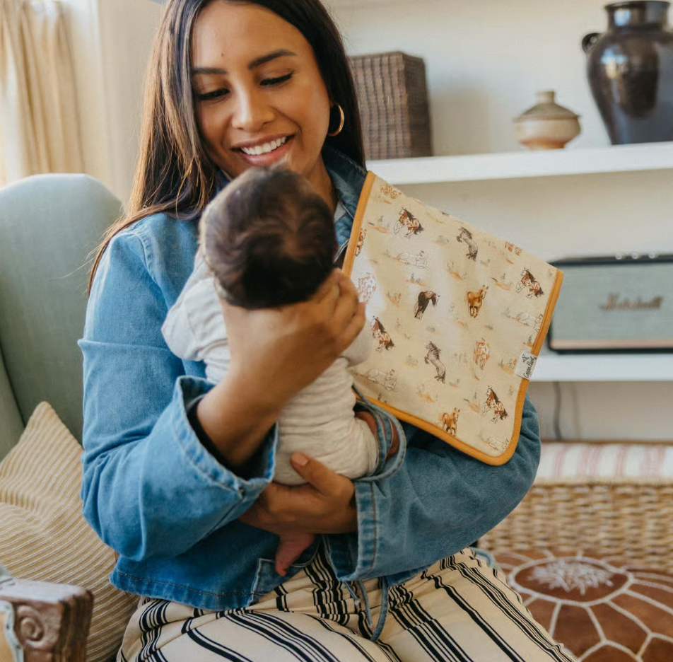 woman holding baby with horse print burp cloth