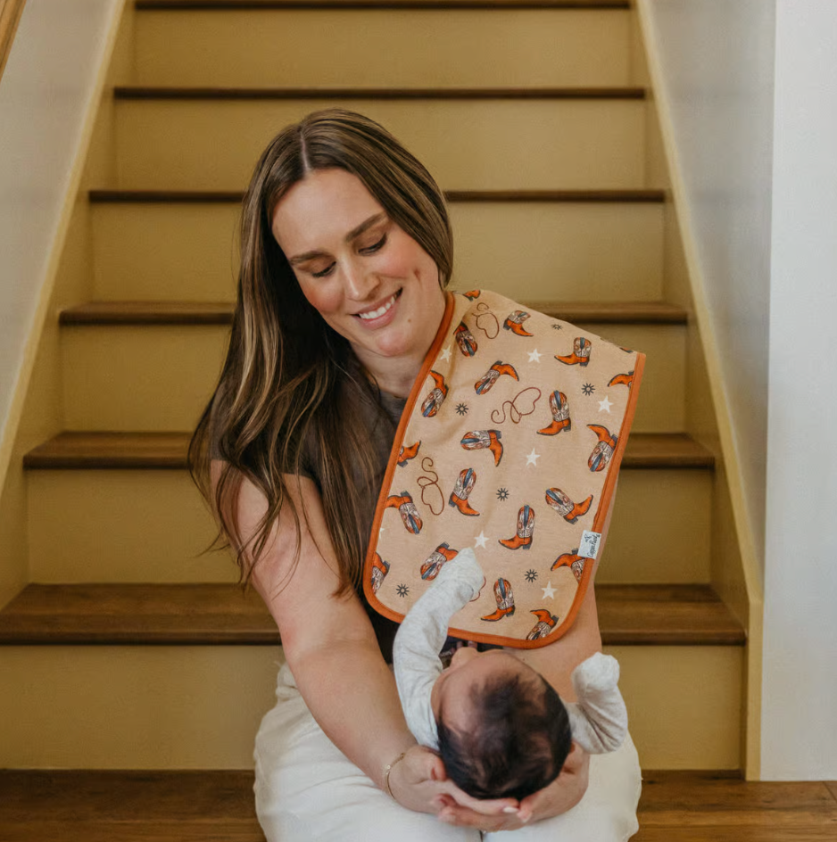 woman sitting on stairs holding infant with western print burp cloth