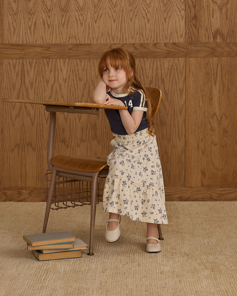 Young girl sitting at a vintage desk with a wooden wall background